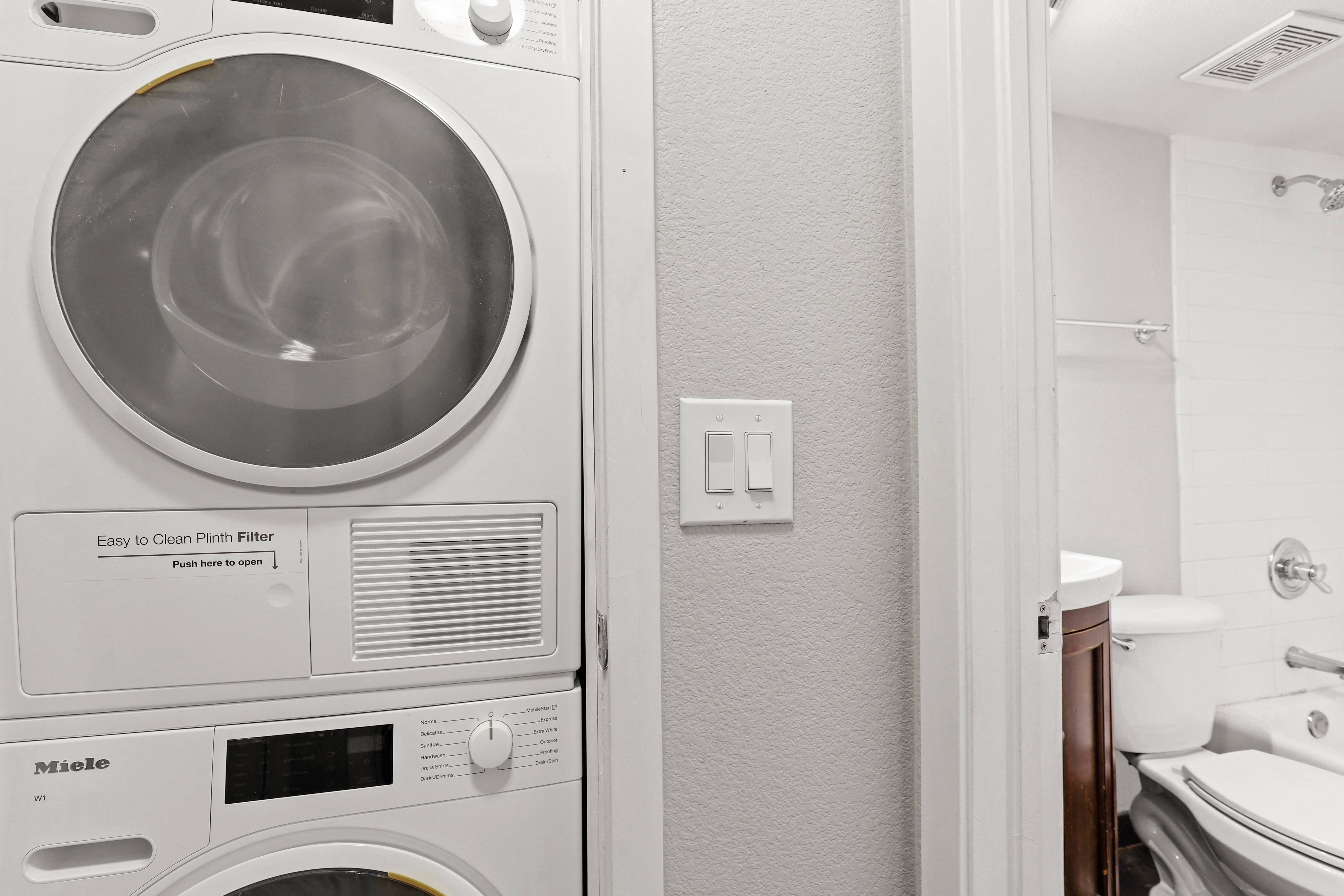 a washer and dryer in a bathroom with a toilet and sink